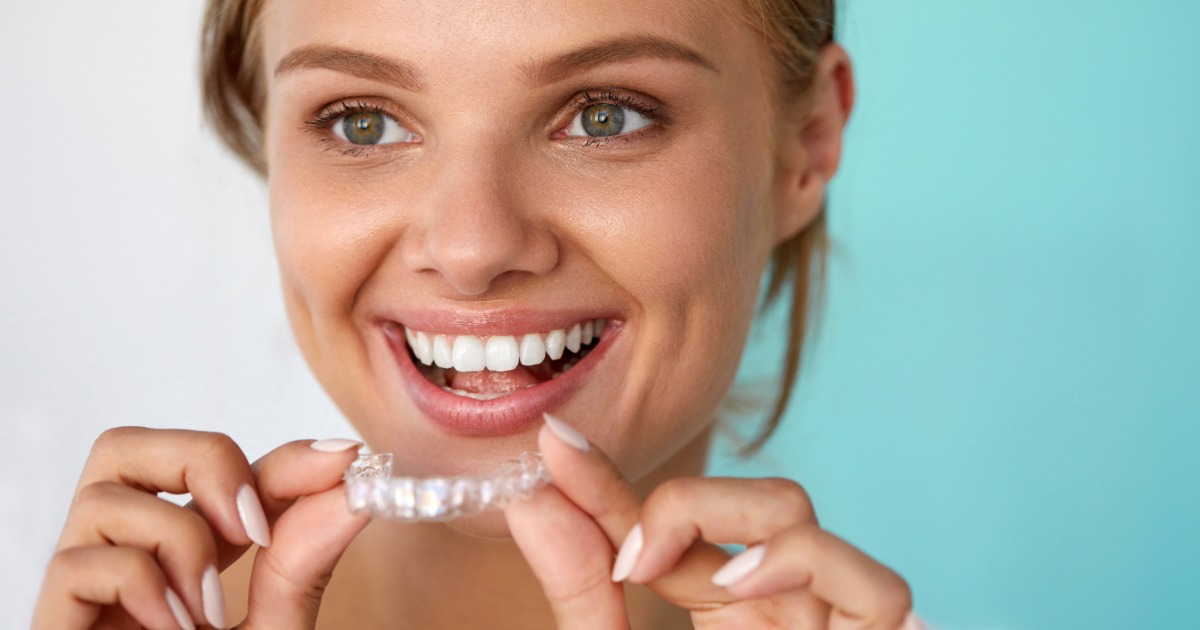 a woman smiling and holding a teeth whitening tray
