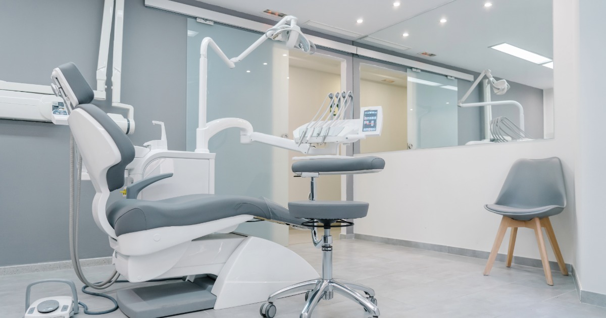 an empty dental surgery with dentist chair, instruments and arm chair